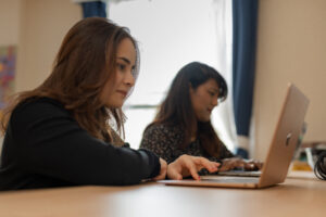 Two people sitting at a desk with their laptops open