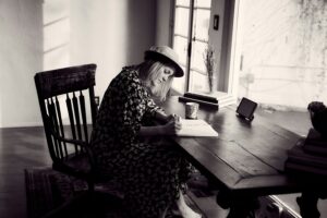 A black and white photo of a woman typing one her laptop