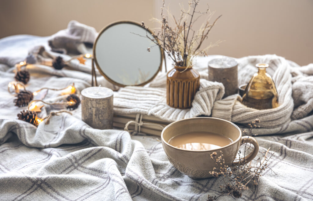 Cozy autumn composition with a cup of coffee, a mirror and candles in the bed.