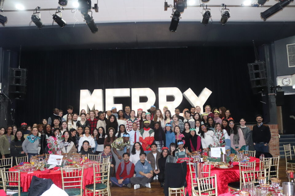 Group of ISH students in front of a "Merry Christmas" sign.