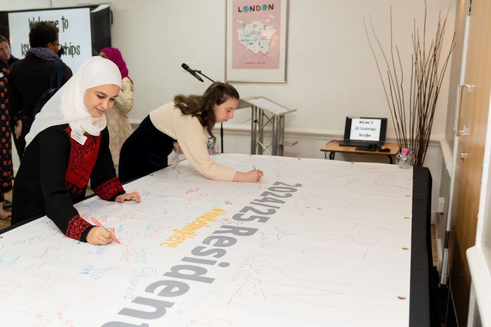 Two students signing ISH welcome back banner.