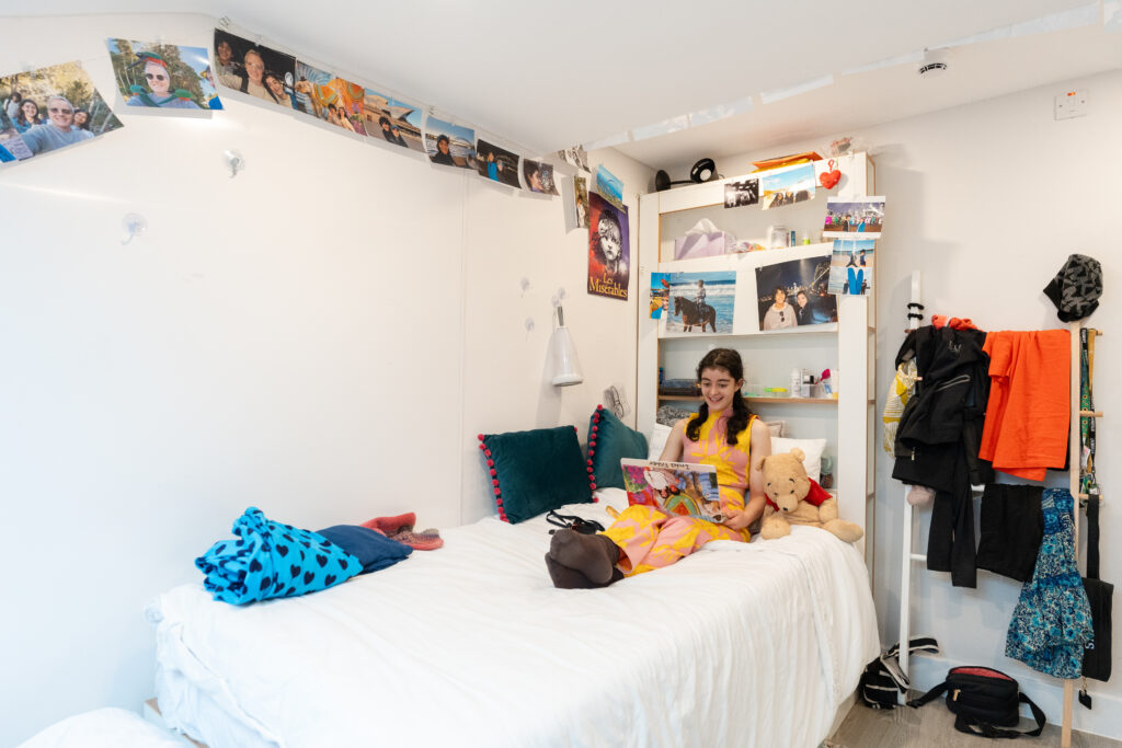 A girl sitting on her bed in her room.