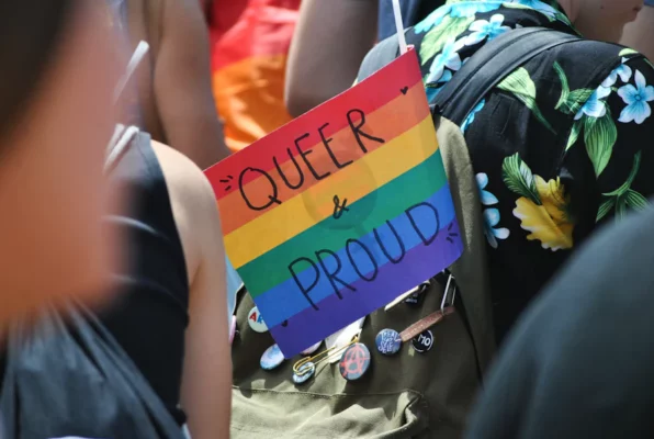 A person wearing a picture that say queer and proud