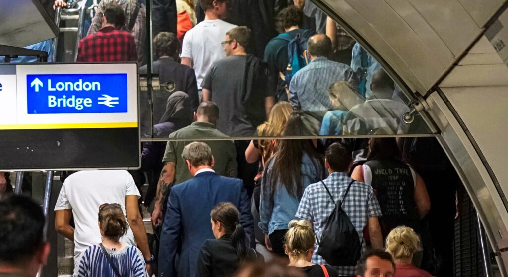 commuters walking shoulder to shoulder up the stairs 