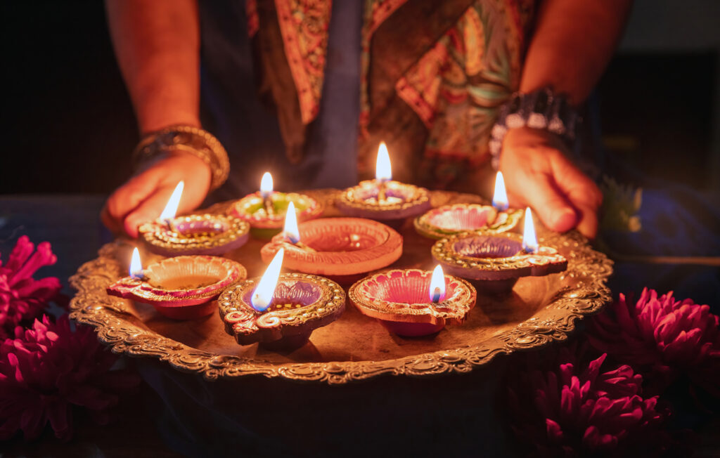 Diwali. Woman holding a tray with Diya oil lamps lit,