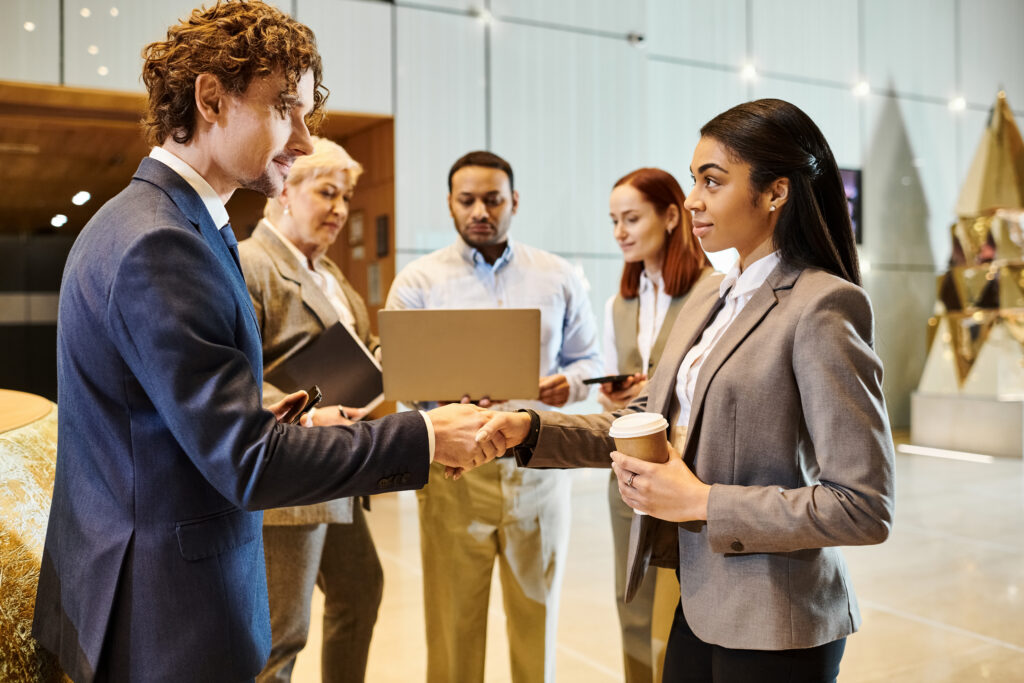 An interracial man and woman in business attire shaking hands.