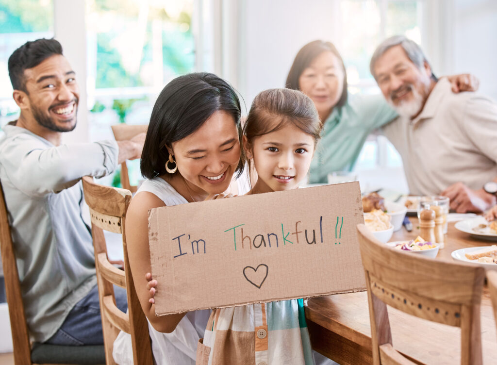 Shot of a little girl holding a sign while having lunch at home.