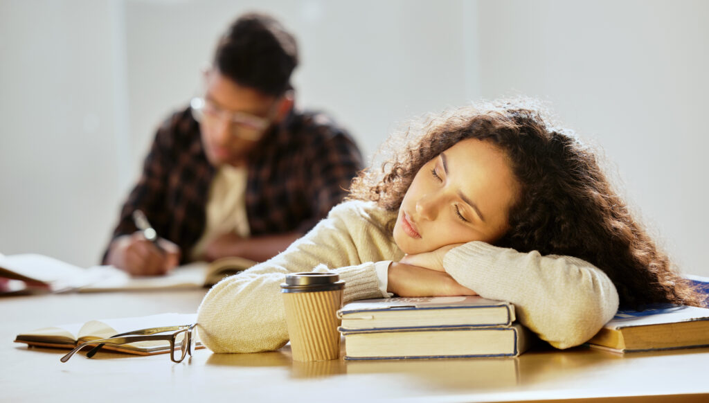 Cropped shot of an attractive young female college student sleeping on her textbooks in class.